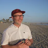 Ullrich wearing a cap, standing on the beach and blinking into the sun.